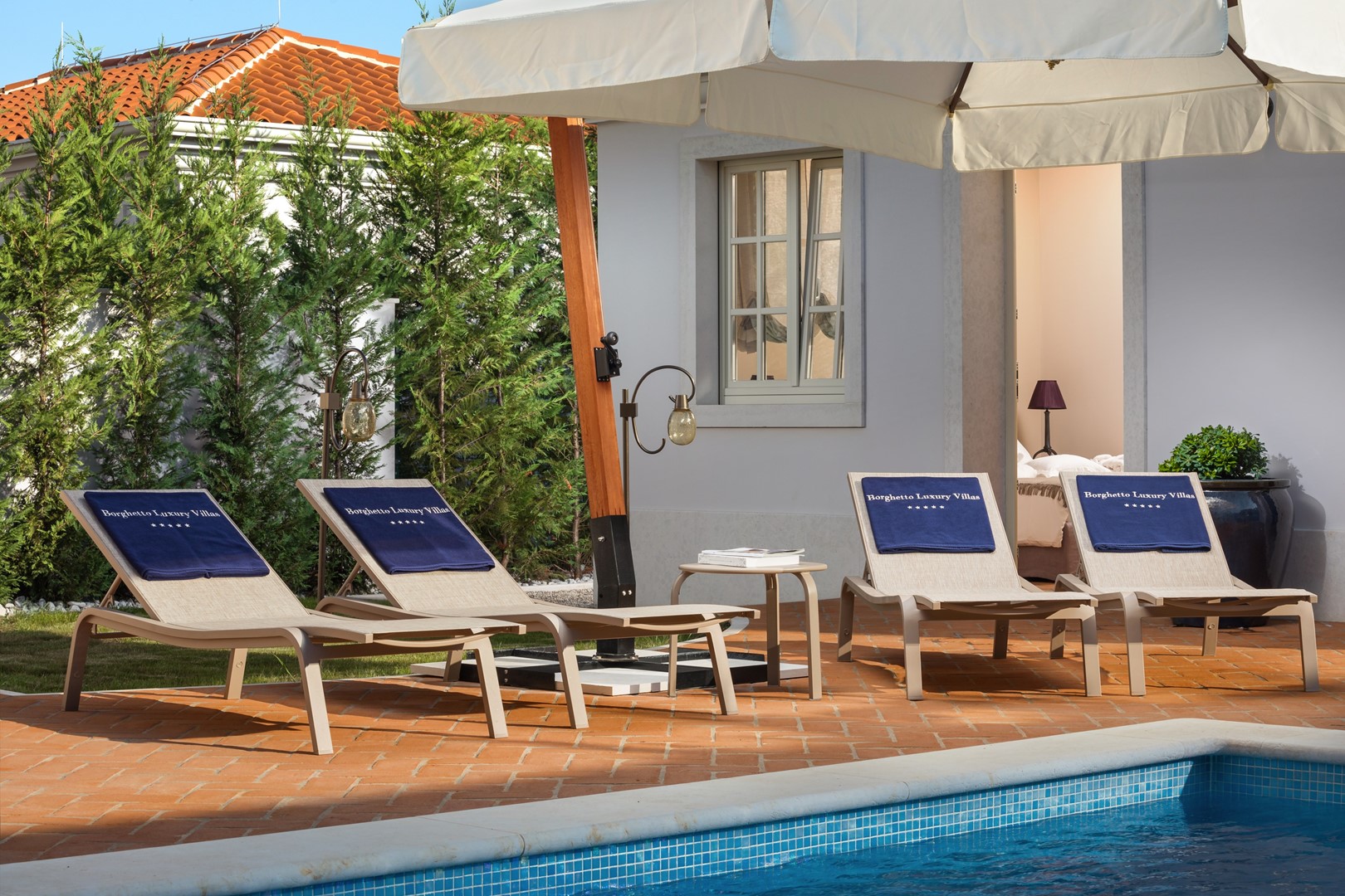 Vanjska terasa sa suncobranom i ležaljkama za sunčanje pored privatnog bazena u luksuznoj vili Celeste u mjestu Vabriga u Istri
