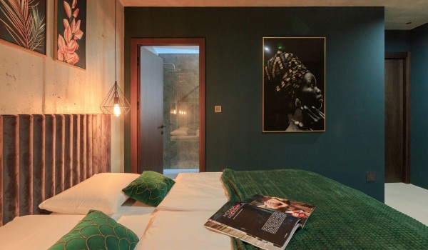 A double bed with emerald green bedding and green walls decorated with artistic paintings in a luxury holiday villa on the island of Krk