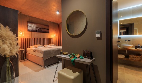A room decorated in brown tones with a double bed, a coffee table and a stool, and an en suite bathroom.