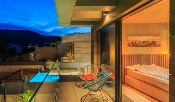 Balcony with garden seats and a view of the garden and pool of the luxury villa Krk Baska II in Baška on the island of Krk