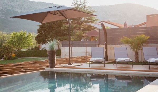 Heated swimming pool with sun deck and deck chairs with umbrellas in the luxury villa Krk Baska II on the island of Krk