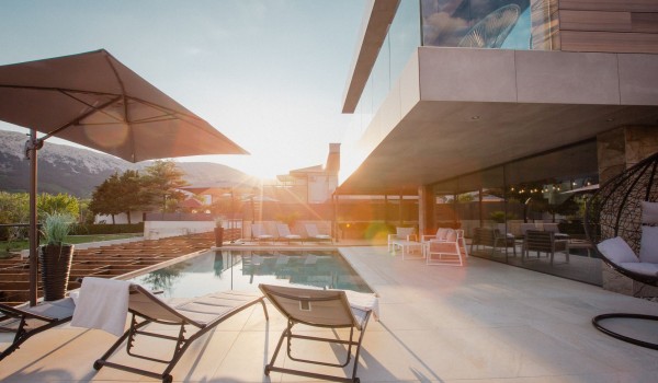 Outdoor terrace with deck chairs, parasol and garden swing by the outdoor pool of the modern villa Krk Baska II on the island of Krk