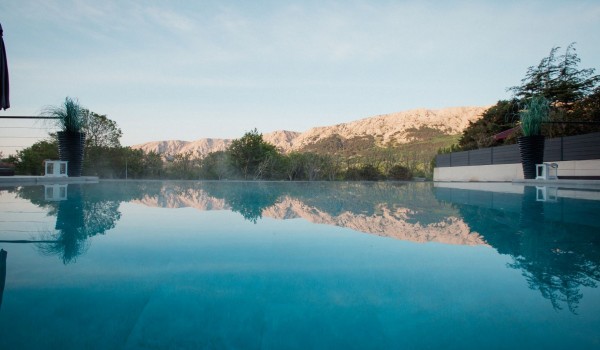 Infinity heated pool of the luxury villa Krk Baska II on the island of Krk is surrounded by greenery and trees
