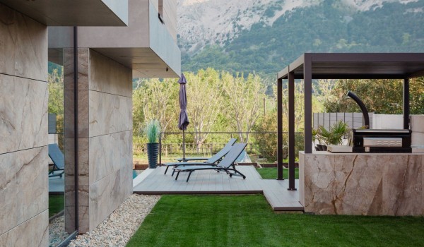 Courtyard with an outdoor covered kitchen and deckchairs for relaxing in a luxury villa on the island of Krk