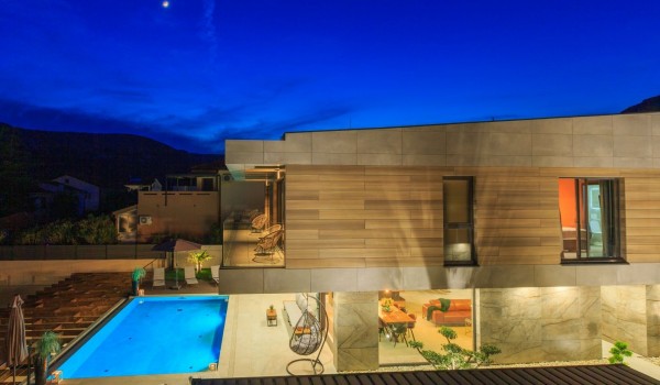 View of the luxurious villa Krk Baska II on the island of Krk with a balcony with garden seats and a swimming pool surrounded by deckchairs