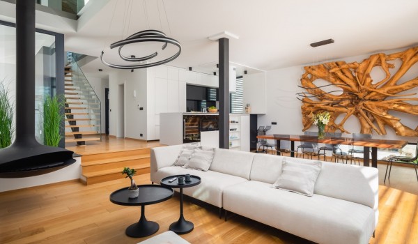 Living area on the ground floor of Villa Idria Sea and View with a fireplace and sofas in the living room behind of which you can see a part of kitchen with kitchen island and a dining area w