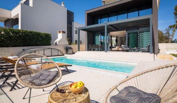 Front of the property with the garden furniture set, sun loungers on the patio around the pool and the terrace with seating and dining area in behind