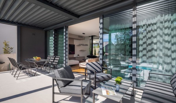 Delicate light on a terrace and large floor-to-ceiling glass wall - terrace entrance to the living area of the Villa Idria Petrcane