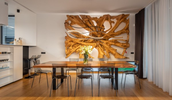 Dining area with a kitchen island on the left and a striking and bold huge decoration on the wall next to the dining set in the front plan