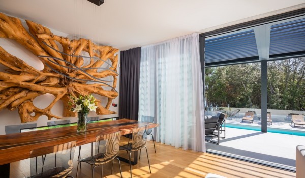 A terrace and pool view from the living area with dining table and 8 chairs and massive statement decoration on the wall