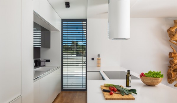 A view on a kitchen with a modern minimalistic hood above the ceramic stove on a kitchen island