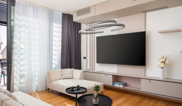 Modern design of a living room with comfortable sofas, SMART LCD TV and popular Playstation 4 gaming console and floor-to-ceiling glass wall