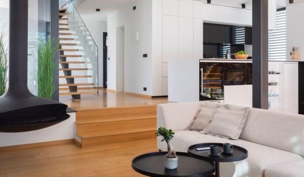Detail from the living room with hanging fireplace and sofas, open staircase and a view of kitchen on the ground floor of the Villa Idria
