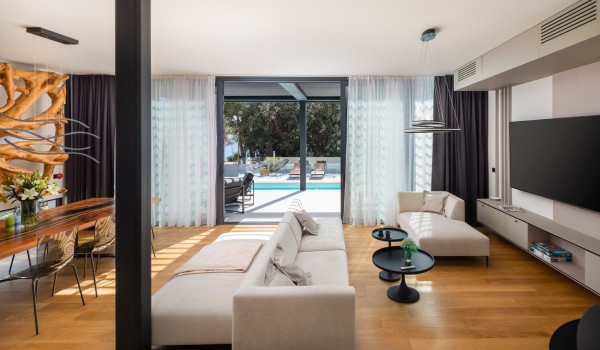 Living area - Living room with sofas and a coffee table, SMART TV and a dining set, subtle daily light that shines through opened framed large wall windows enhance the beauty of the modern de