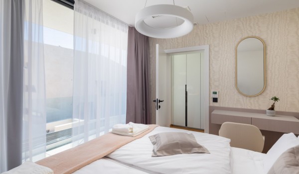 Modern bedroom on the first floor of the Villa with air conditioning, a king size bed, a mirror, a desk with a chair and a balcony