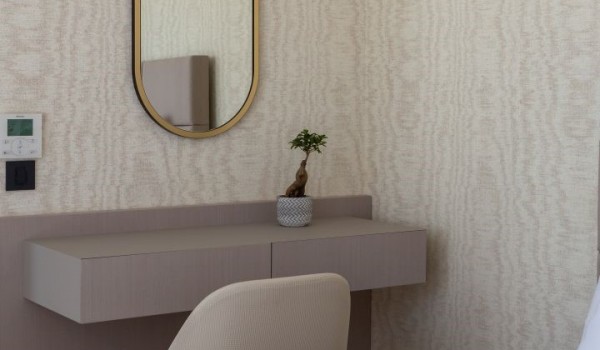 A mirror on the wall with interesting beige wallpapers of the bedroom with a king size bed and an en suite bathroom located on the first floor of the Villa Idria Sea and View Petrcane