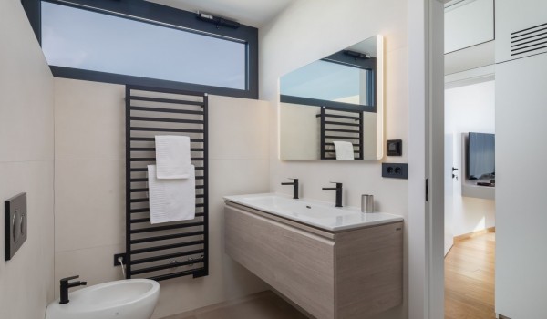 Toilet area of the bathroom with underfloor heating, a sink with a mirror and a bidet, a bedroom position shown through the doors