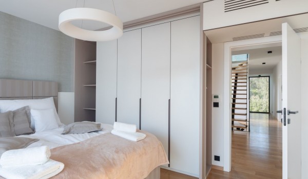 A bedroom on the first floor of the Luxury Villa Idria Sea and View Petrcane with a storage space in the shelved floor-to-ceiling wardrobe and the doors to the staircase lobby of the floor