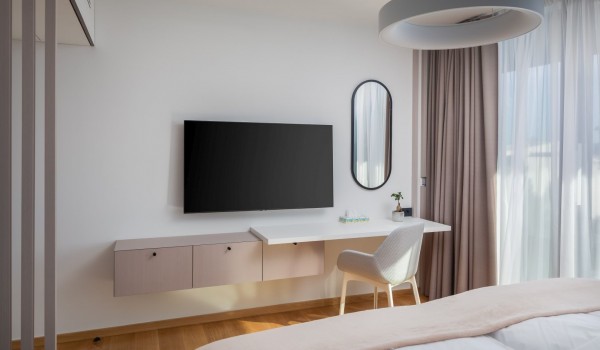 Modern interior of the bedroom located on first floor with a contemporary chandelier and mirror, desk with a chair and two cabinets, LCD TV and a queen sized bed of Luxury Villa Idria Sea and
