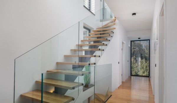 Modern clear glass panels run the length of the staircase, complementing the open-concept of the Luxury Villa Idria Sea and View Petrcane; a view of the first floor with a  large glass wall o