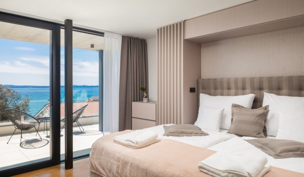 Master bedroom on the second floor of Luxury Villa Sea and View Petrcane with en suite bathroom, queen size bed and beautiful sea view from the private terrace with two chairs and a coffee ta