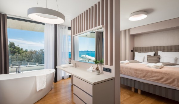 Luxurious master bedroom with en suite bathroom, a sea view from the modern bathtub with the room dividers and floor-to-ceiling glass wall exit for the spacious terrace