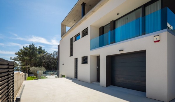 East side of the Luxury Villa Idria Sea and View with a private garage and 4 parking spaces on the ground level, and a balcony of a bedroom with en suite bathroom on the first floor