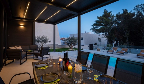 Dining and seating area on the terrace of ground floor with a view on the private pool and greenery
