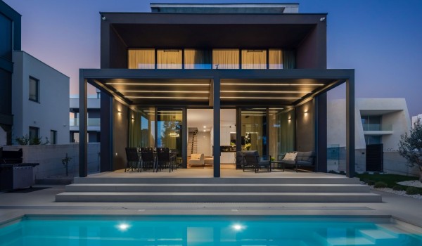 A night view from the heated hydro massage pool on the front of the Villa Idria Sea and View Petrcane with the roofed terrace and the glass wall entrance to the living area
