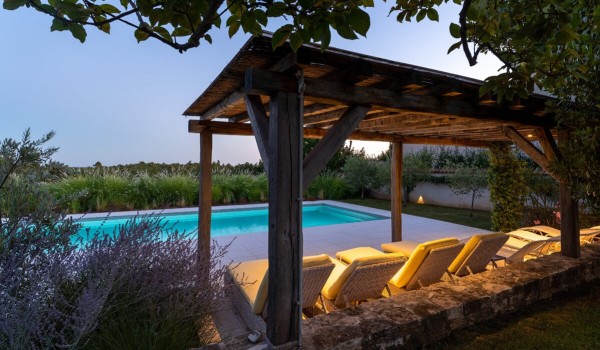 Sun loungers in the roofed part of the terrace next to the private pool of a family villa for vacation and rent in Istria