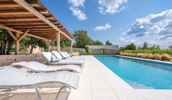 Sun loungers by the private pool on the spacious paved terrace of the family vacation villa Deluxe Manor Baderna