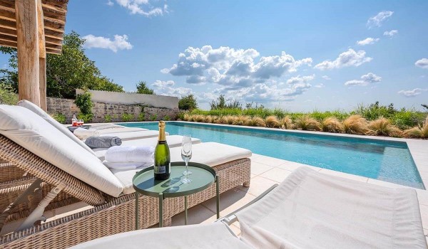 Table with champagne next to sun loungers around the private pool of the luxury rental villa in Radovani