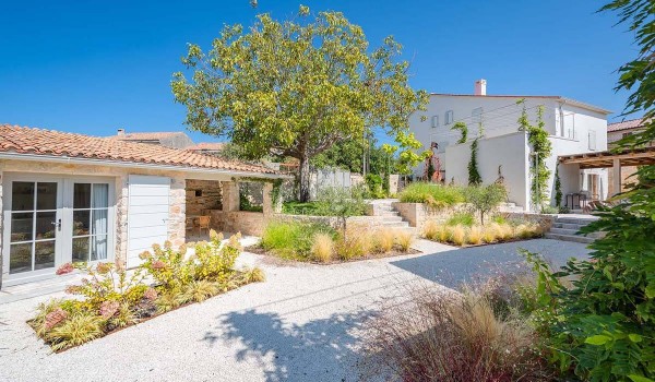 Various plants and a gravel path in a private landscaped garden in front of the stone holiday villa Deluxe Manor Baderna