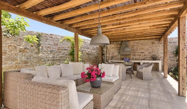 Private roofed patio with outdoor seating, dining table with chairs and outdoor grill in the fenced yard of the stone luxury villa in Istria