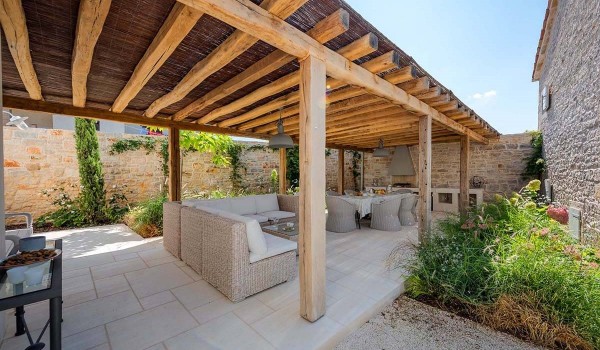 Roofed part of the fenced terrace with barbecue, dining table and chairs and outdoor seating