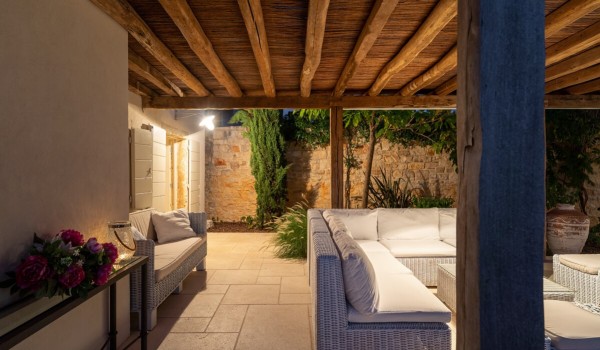 Illuminated rattan sofa in front of the entrance to the luxury villa with pool Deluxe Manor Baderna in Istria