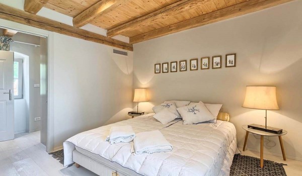 Comfortable double bed in an elegantly decorated bedroom of a luxury stone villa with pool in Istria