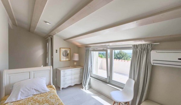 View from the air-conditioned bedroom with single bed to the sunny balcony with a view of the landscaped yard of the luxury holiday villa with pool