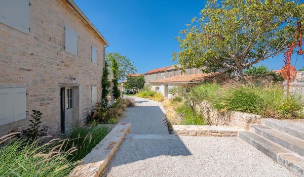 Gravel path through a landscaped yard with a garden in front of a family villa with pool in Radovani
