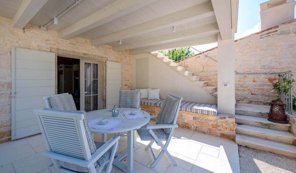 Roofed terrace with outdoor table and benches and entrance to the ground floor of the guest house