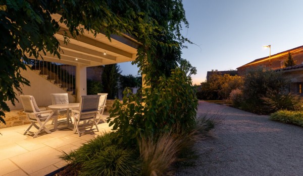 Greenery in the landscaped garden of the stone family villa with pool Deluxe Manor Baderna and a table with chairs in the roofed part of the terrace