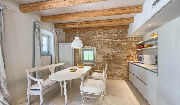 Rustically decorated kitchen with a wooden dining table and kitchen utensils in the luxury holiday villa Deluxe Manor Baderna