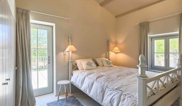 Interior of a bedroom with a double bed and access to a balcony with a view of a private garden