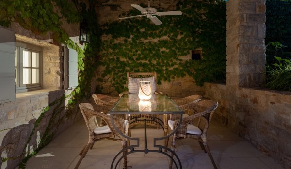 Outdoor dining table with chairs on the roofed terrace in front of the pool house in the yard of a luxury villa for rent and vacation in Istria