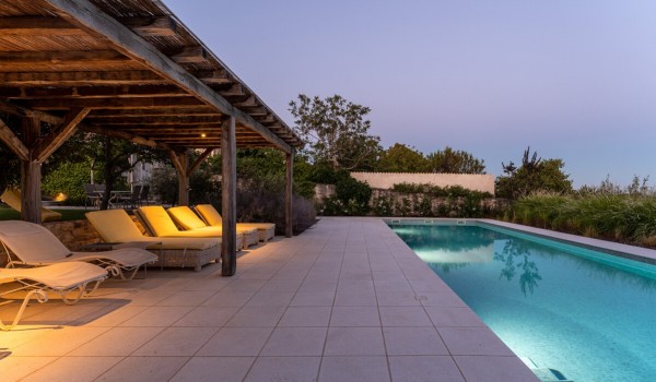Paved terrace with a private illuminated pool with sun loungers in the fenced yard of a family holiday villa in Istria