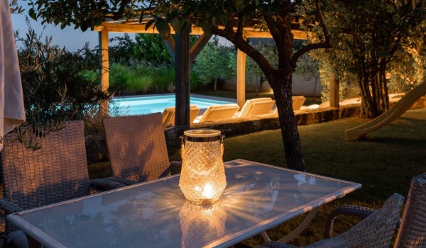 View of the private pool from the outdoor dining table in the landscaped garden of the luxury family villa Deluxe Manor Baderna in Istria
