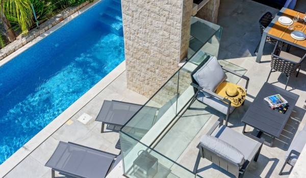 The outdoor living area of the beach front Šolta luuxury villa with concierge service  for a luxurious vacation with a swimming pool, a lounge area for rest and dining, and a barbecue for 8 p