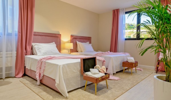 A modernly decorated bedroom with two separate beds, an armchair and SAT TV in a villa with a swimming pool for vacation Raquel by the beach with private pool and a gym