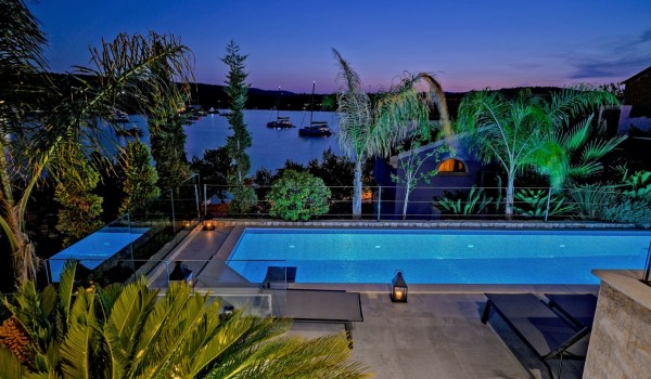 Illuminated swimming pool with deckchairs overlooking the sea of the family villa for rent and vacation Raquel on the island of Šolta