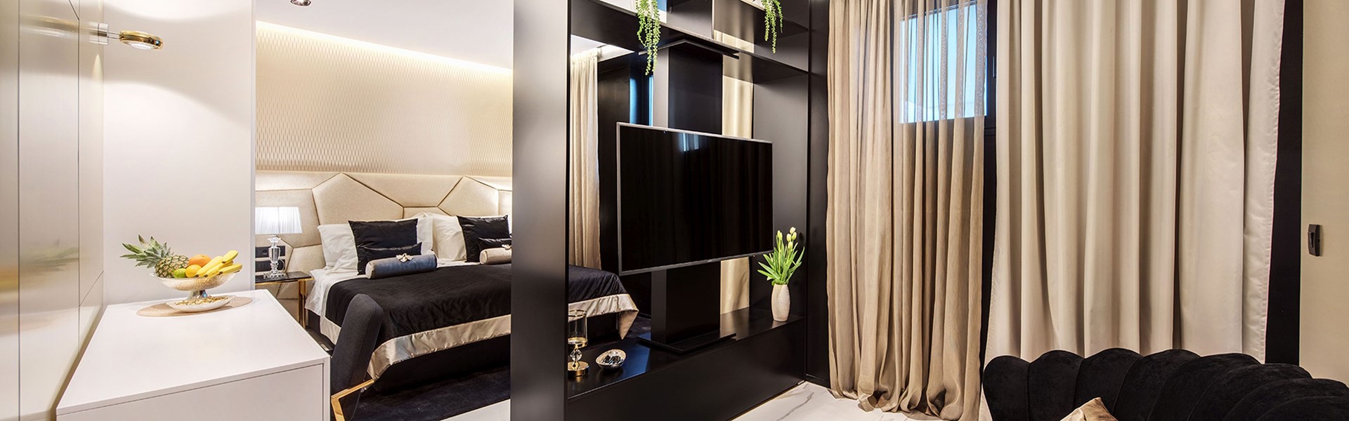 Interieur des Luxusapartments Split Gem Charm mit Doppelbett und Wohnzimmer mit Sesseln und LCD-TV